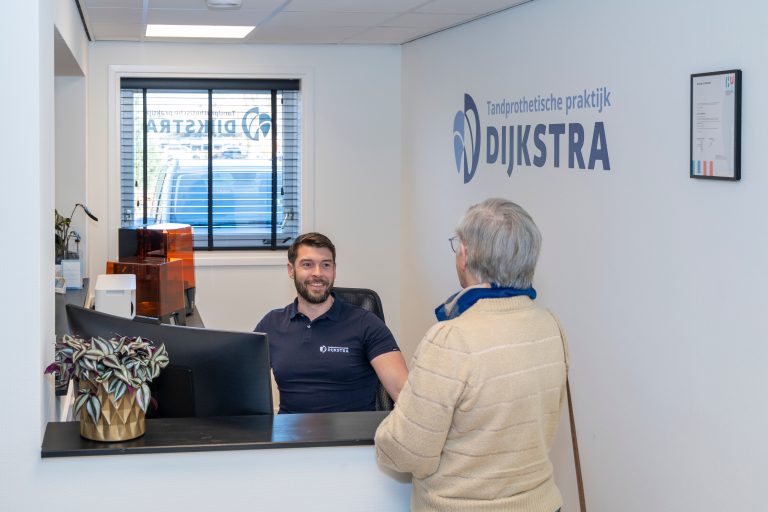 Medewerker adviseert klant aan balie van TPP Dijkstra kantoor tijdens persoonlijk gesprek