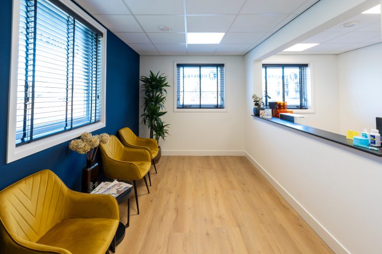 Moderne wachtkamer met gele stoelen en houten vloer bij TPP Dijkstra tandprothetische praktijk