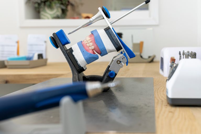 Kunstgebit in een articulator met een handstuk op de voorgrond in het laboratorium