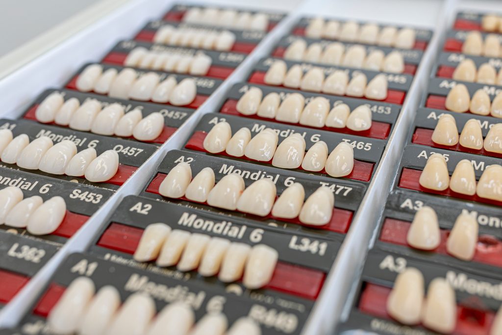 Verschillende kunstgebit tandsets gerangschikt in vakken, met verschillende tandkleuren en -vormen voor protheses