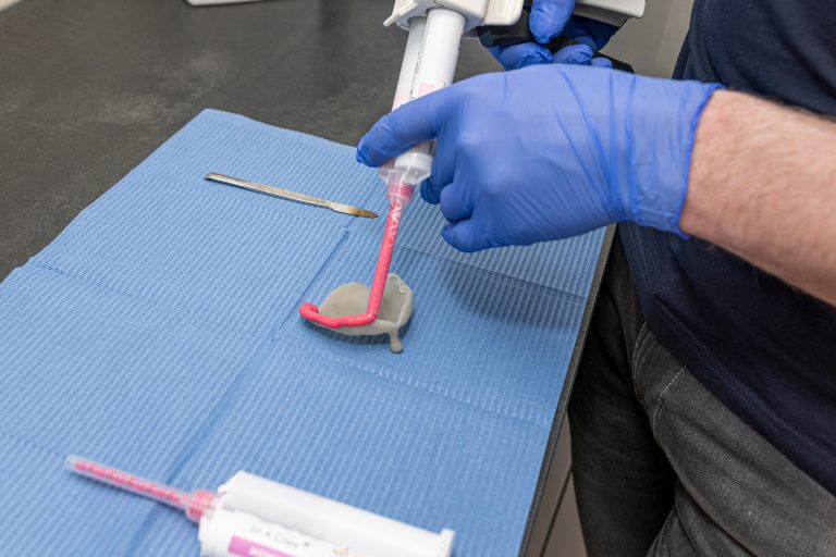 Roze afdrukmateriaal wordt uit een patroon op een afdruklepel aangebracht